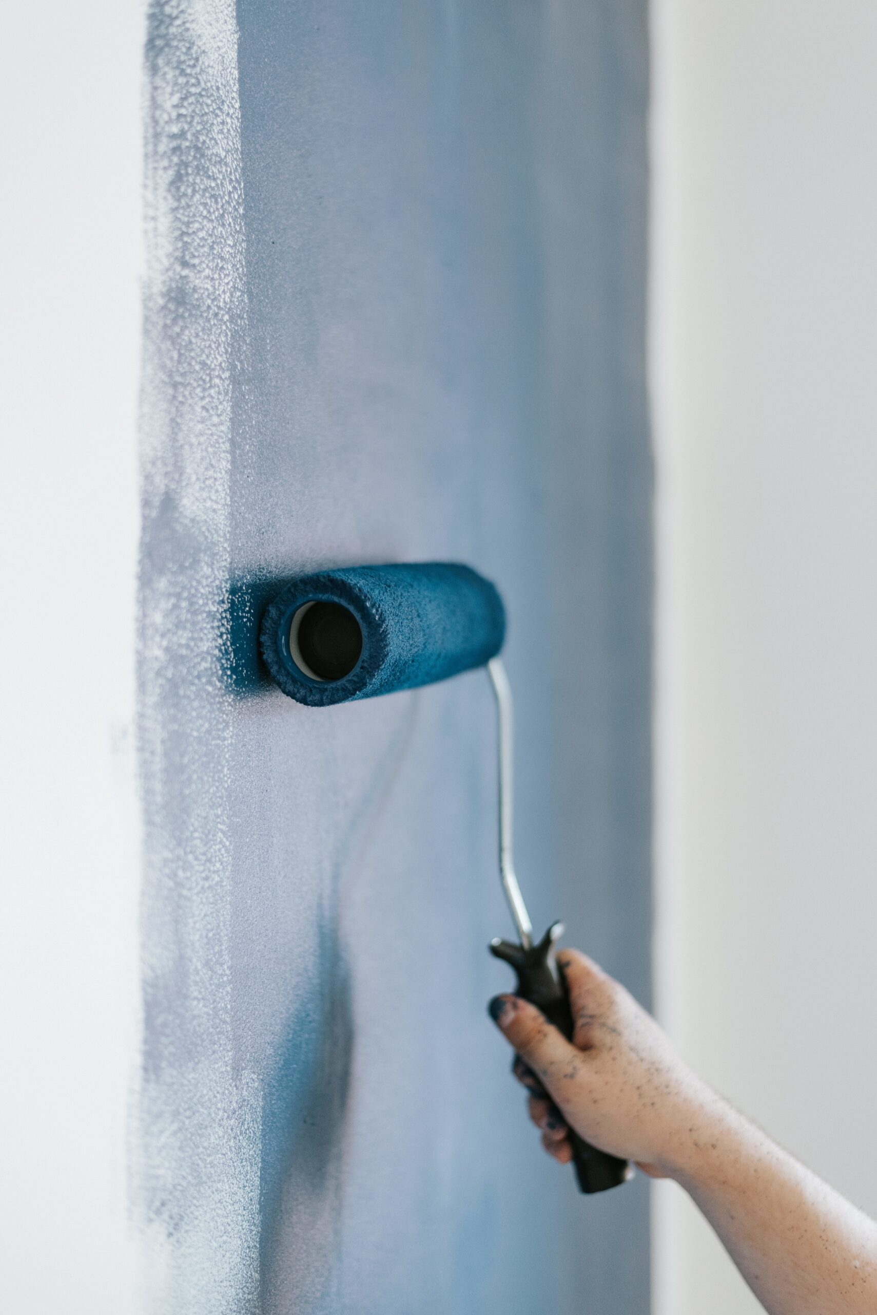 closeup shot of a female using paint rollers with the color blue